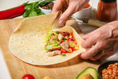 Adam lezzetli bir burrito hazırlıyor.