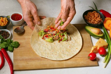 Adam lezzetli bir burrito hazırlıyor.