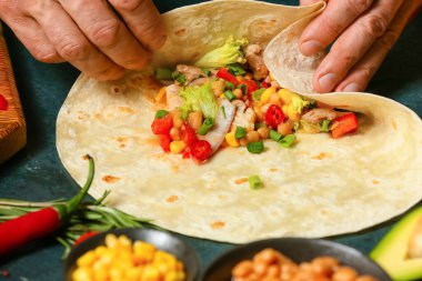 Lezzetli bir dürüm hazırlayan adam, masada et var, yakın plan.