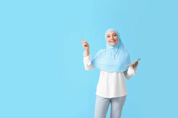 Muslimische Sekretärin Mit Taschenrechner Zeigt Auf Etwas Auf Farbigem Hintergrund — Stockfoto