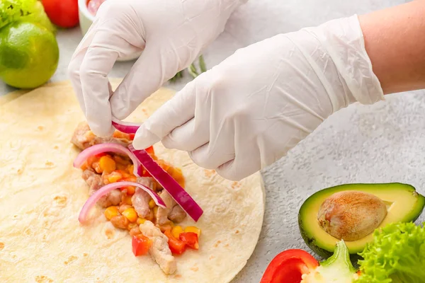 Hafif arka planda etli lezzetli burrito hazırlayan kadın, yakın plan.