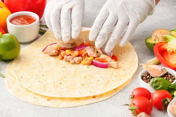 Kadın hafif arka planda etli lezzetli burrito hazırlıyor.