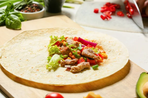 Beyaz arka planda lezzetli dürüm hazırlamak için taze malzemeli tortilla.