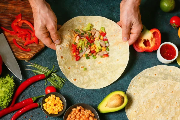 Adam lezzetli bir burrito hazırlıyor.