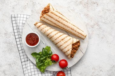 Lezzetli burritoları ve hafif arka planda sosu olan bir pano.