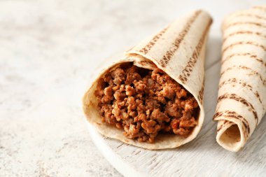 Hafif arka planda lezzetli burritoları olan tahta, yakın plan