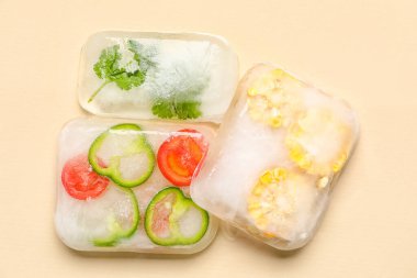 Bej arka planda buzda donmuş taze sebzeler.