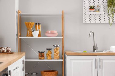 Mutfaktaki ışık duvarının yanında bulaşık takımı ve tezgahları olan modern raf ünitesi