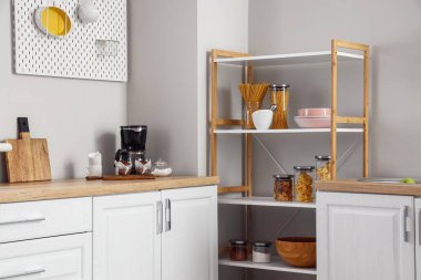 Modern raf ünitesi ve mutfak duvarının yanındaki kahve makinesiyle.