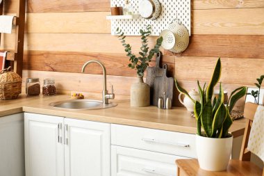 Lavabolu tezgahlar ve ahşap duvarın yanında farklı yemek takımları.