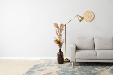 Işık duvarının yanında modern lamba olan yeni kanepe.