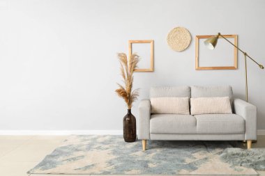 Işık duvarının yanında modern lamba olan yeni kanepe.