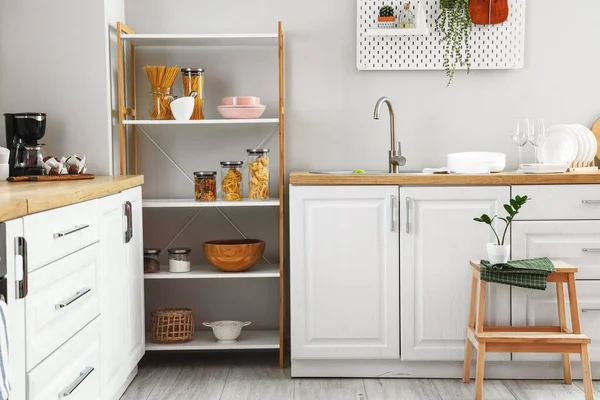 Mutfaktaki ışık duvarının yanında bulaşık takımı ve tezgahları olan modern raf ünitesi