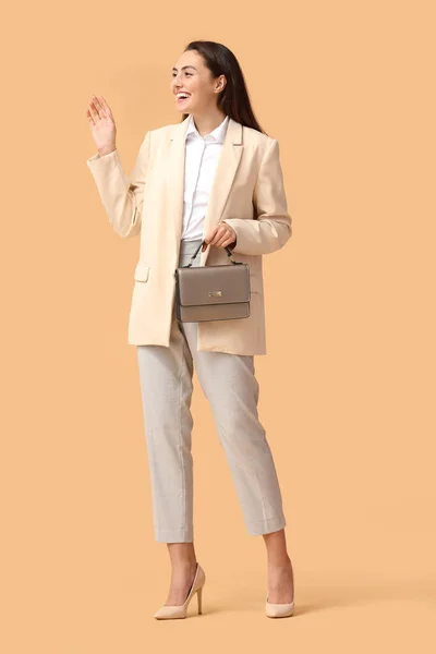 带着米色背景包的快乐年轻女商人 — 图库照片