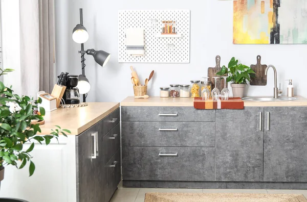 Gümüş lavabolu ahşap tezgahlar ve hafif mutfakta yemek takımı.