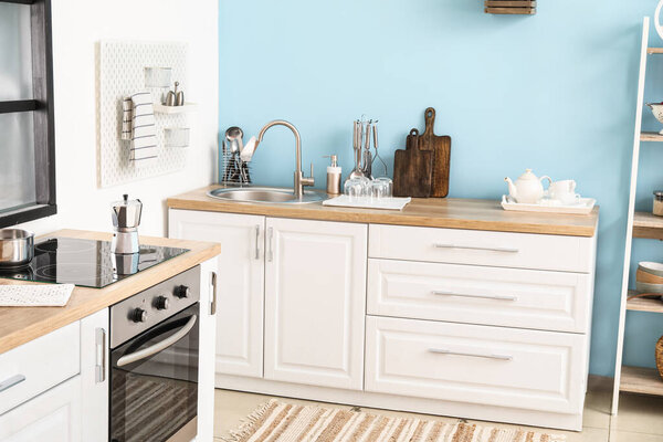 Деревянные столешницы с серебряной раковиной и посудой на кухне