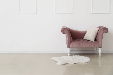 Beyaz duvarın yanında yastıklı yeni pembe kanepe