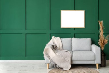 Yeşil duvarın yanında sıcak ekoseli yeni kanepe