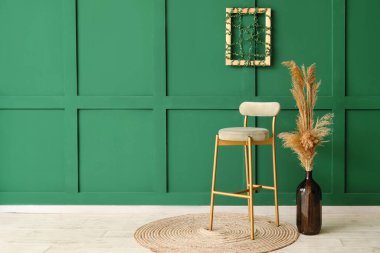 Yeşil duvarın yanında otlu vazo ve yeni sandalye.