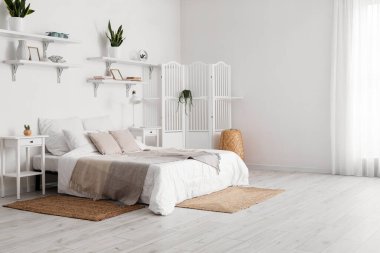 Şık yatak odasının içinde komodinleri, katlanır perdeleri, çiçekleri ve lambaları var.