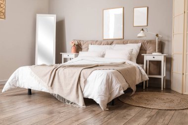 Ayna ve boş posterli şık bir yatak odası.