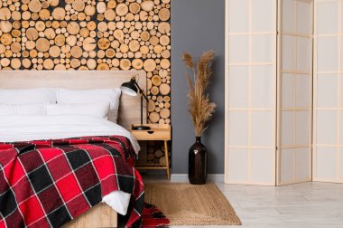 Rahat yatak ve modern lamba komodinin üstünde.