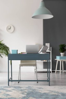 Modern dizüstü bilgisayarlı iş yeri ve şık ofis içi sabit hatlı telefon.