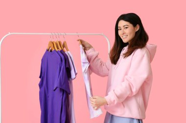 Genç Asyalı kadın ve pembe arka planda t-shirtleri olan göğüsler.