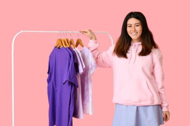 Genç Asyalı kadın ve pembe arka planda t-shirtleri olan göğüsler.