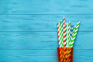 Mavi ahşap arka plandaki içecekler için şık pipetli cam.