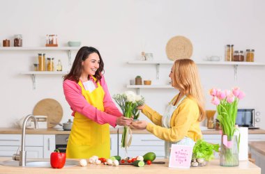 Genç bir kadın mutfakta Uluslararası Kadınlar Günü için annesini selamlıyor.