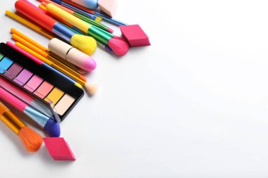 Farklı kozmetik ürünleri ve makyaj fırçaları beyaza izole edilmiş.
