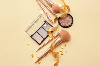 Açık renk arka planda kozmetik ürünleri ve makyaj fırçaları ile kompozisyon, üst görünüm