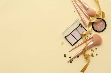 Açık renk arka planda kozmetik ürünleri ve makyaj fırçaları ile kompozisyon, üst görünüm