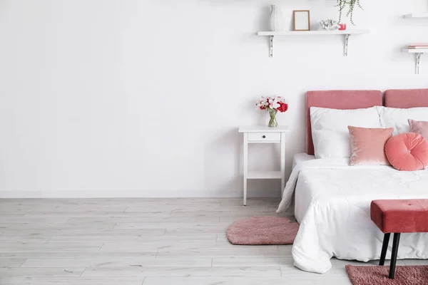 Άνετο Κρεβάτι Κομοδίνο Και Βάζο Λουλούδια Κοντά Λευκό Τοίχο — Φωτογραφία Αρχείου