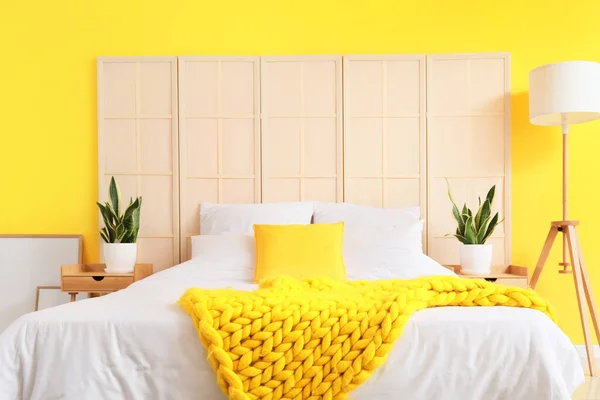 快適なベッド 観葉植物 黄色の壁の近くのモダンなランプ — ストック写真