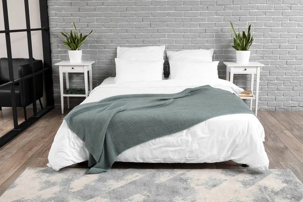 靠近灰色砖墙的舒适的床 地毯和床头柜 — 图库照片