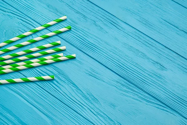 Mavi ahşap arka plandaki içecekler için şık pipetler