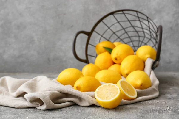 Gri masada taze limonlarla çevrilmiş sepet.