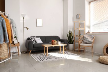 Siyah kanepe ve kalın ceketlerle aydınlık odanın içinde.