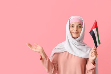 Geleneksel giyinmiş genç bir kadın ve arka planında BAE bayrağı var.