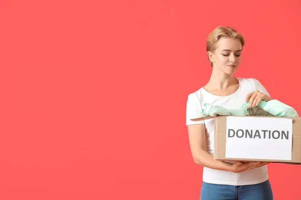 Young Woman Holding Box Donation Clothes Red Background — Stock Photo, Image