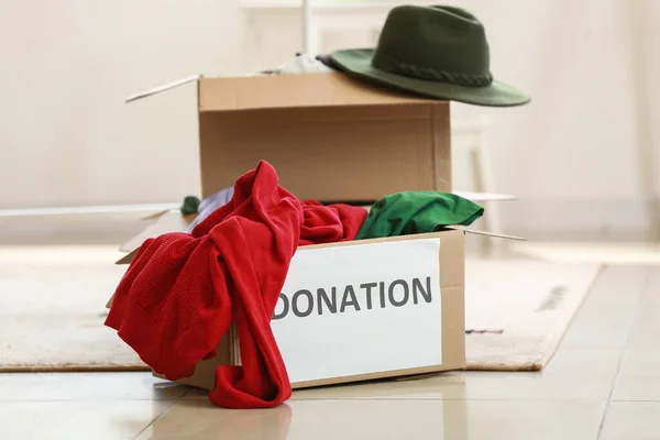 Cardboard boxes with clothes for donation in room