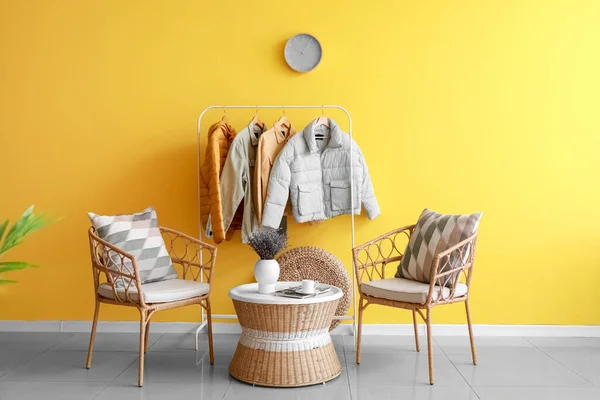 快適な椅子と色の壁の近くのジャケットとハンガー付きの部屋のインテリア — ストック写真