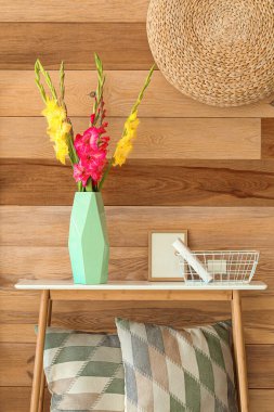 Güzel gladiolus çiçekli vazo, sepet ve ahşap duvarın yanındaki boş çerçeve.