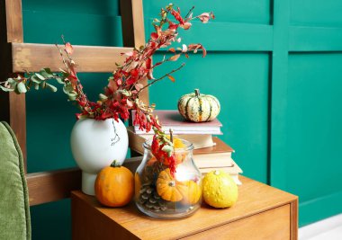 Kitaplar, balkabakları ve vazolar odada sonbahar dalları olan