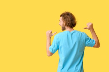 Sarı arka planda şık tişörtlü yakışıklı genç adam.