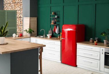 Modern mutfağın içinde şık buzdolabı ve tezgahlar var.