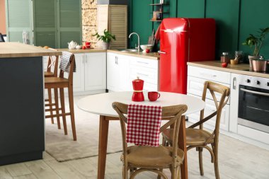 Modern mutfak, yemek masası, şık buzdolabı ve tezgahlar.