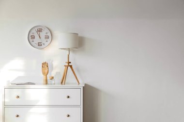 Lamba, dekor ve saatli çekmeceler duvarda asılı.
